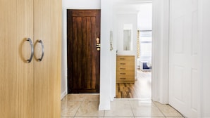 Un pasillo con una puerta de madera, una puerta blanca y un armario de madera.