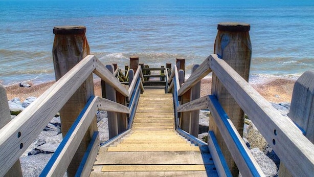 Una scala di legno che conduce a una spiaggia con vista sull'oceano.