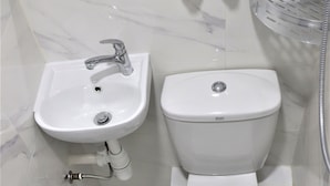 A bathroom with a white sink, a toilet, and a shower area. - W's Lounge (Kowloon)