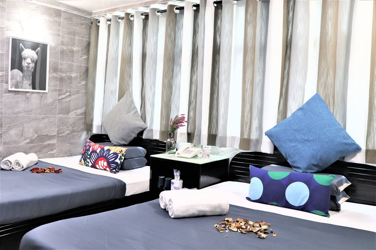 A hotel room with two beds, a small table with amenities, a mirror, and a curtain.
