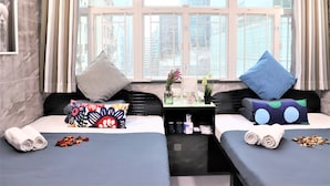 A hotel room with two beds, a small table with toiletries, and a window with curtains. - W's Lounge (Kowloon)