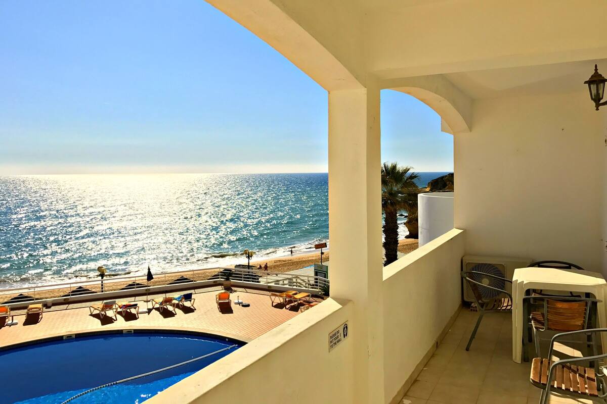 A balcony with a pool, chairs, and a view of the sea.