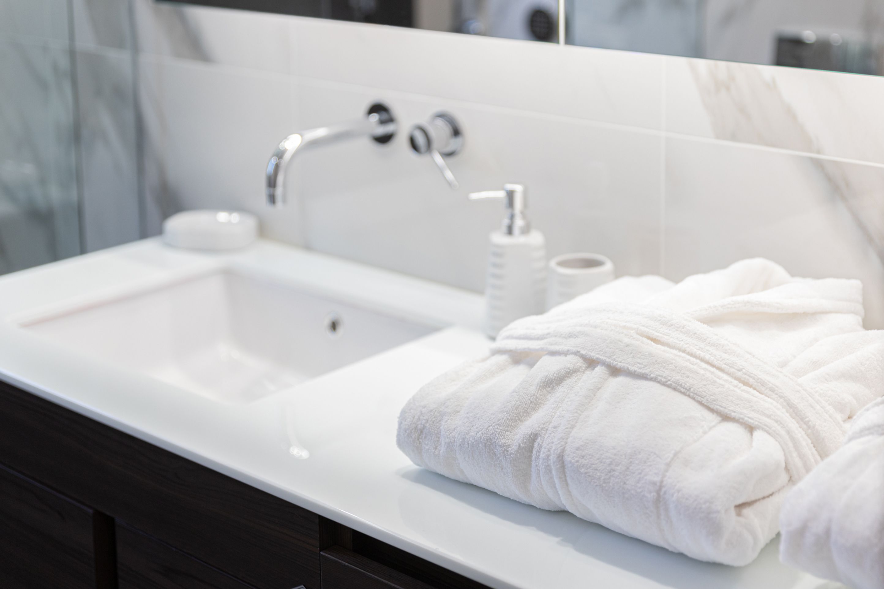Un baño moderno con un lavabo blanco, un espejo y una toalla.
