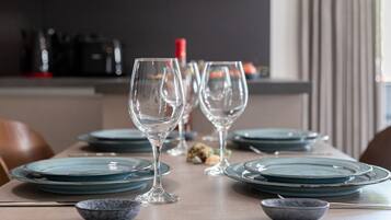 A dining table set with clear glassware and teal plates, with a kitchen in the background.