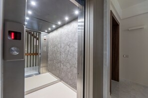 Et interiør af en elevator med en marmorvæg og en trædør.
