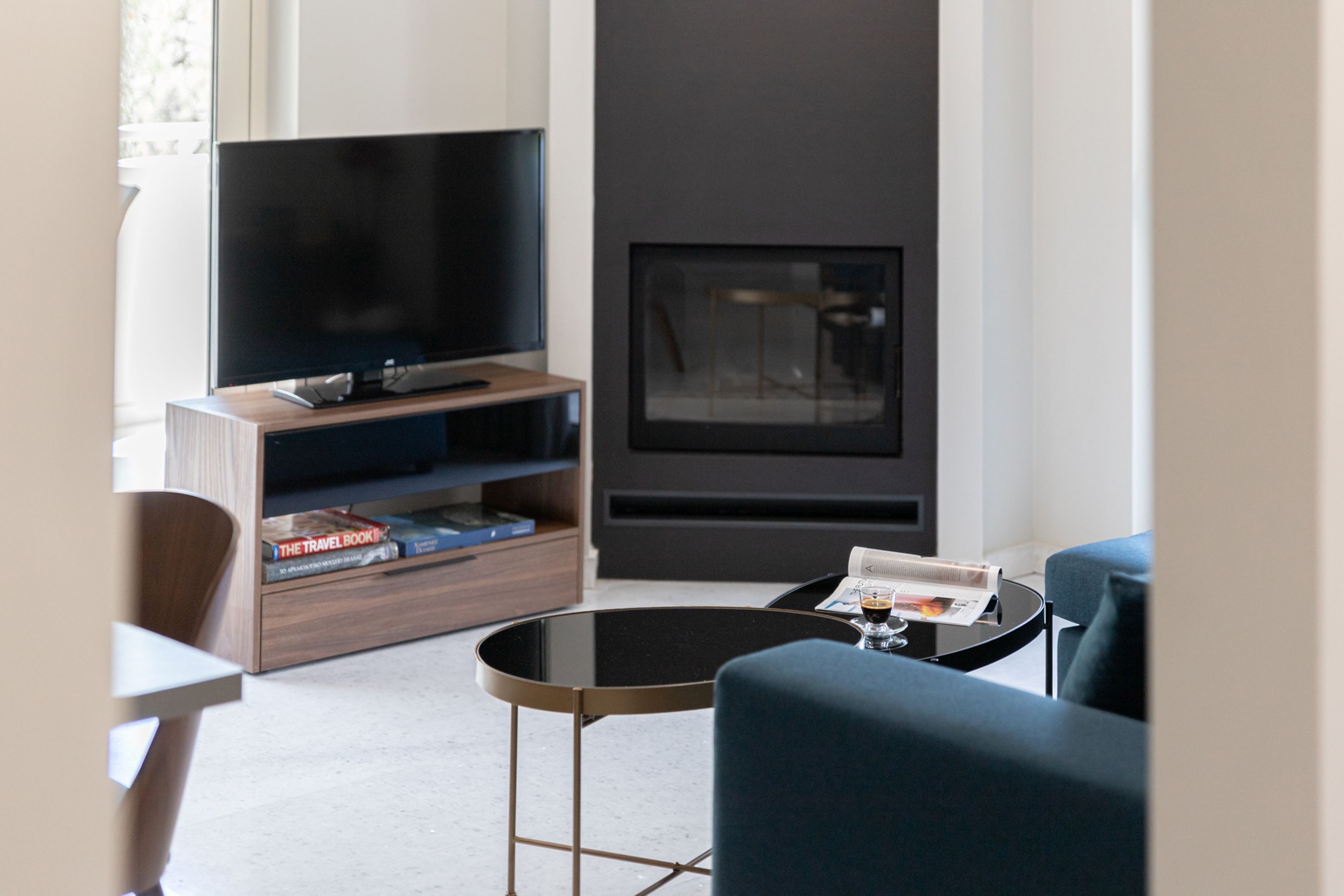 A modern living room with a flat-screen TV, a fireplace, a coffee table, and a bookshelf with books.