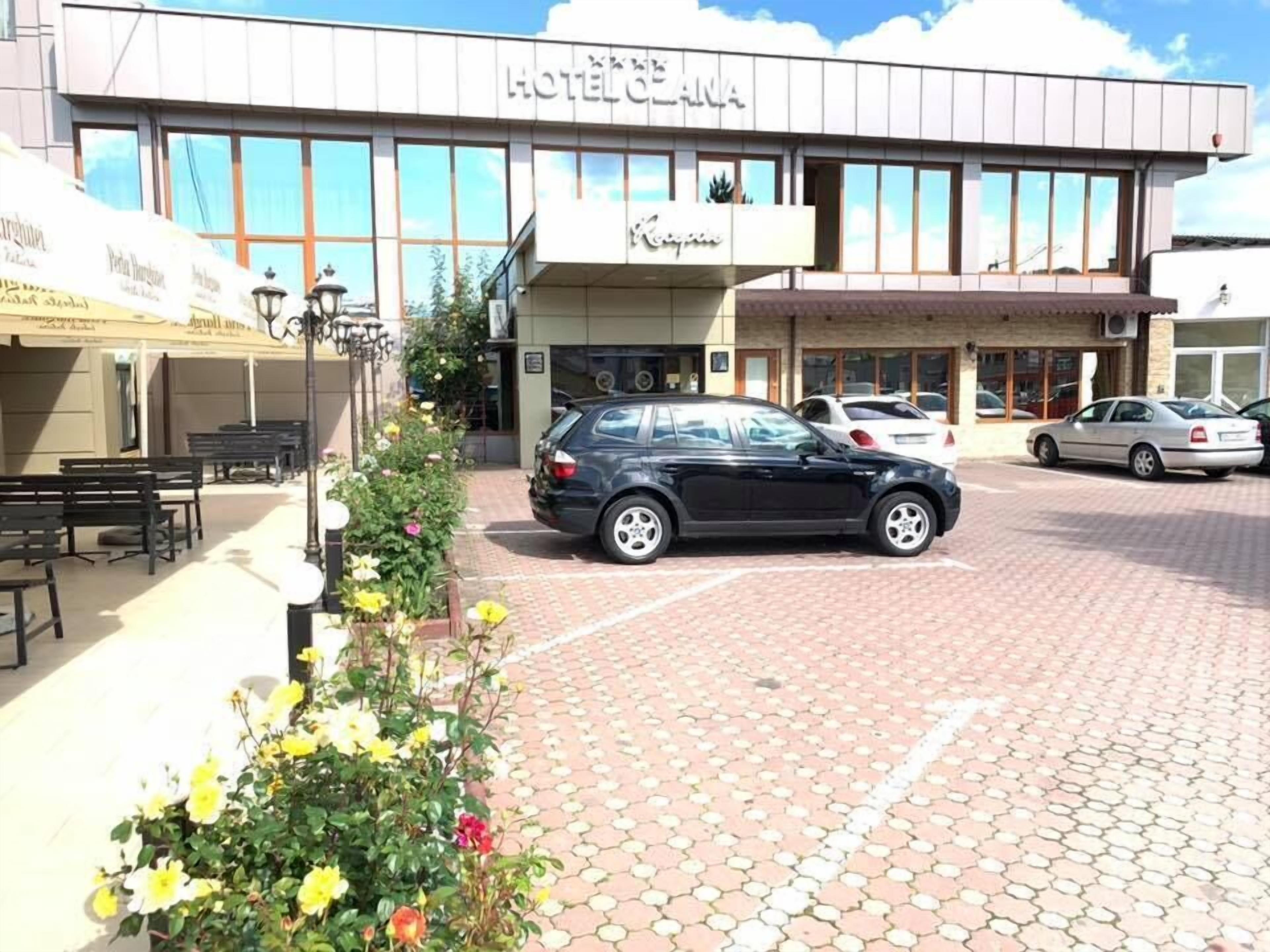 Un hôtel doté d’une façade moderne, d’un parking et d’un parterre de fleurs.