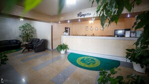 Een receptie met een receptiebalie, een klok en een plant.