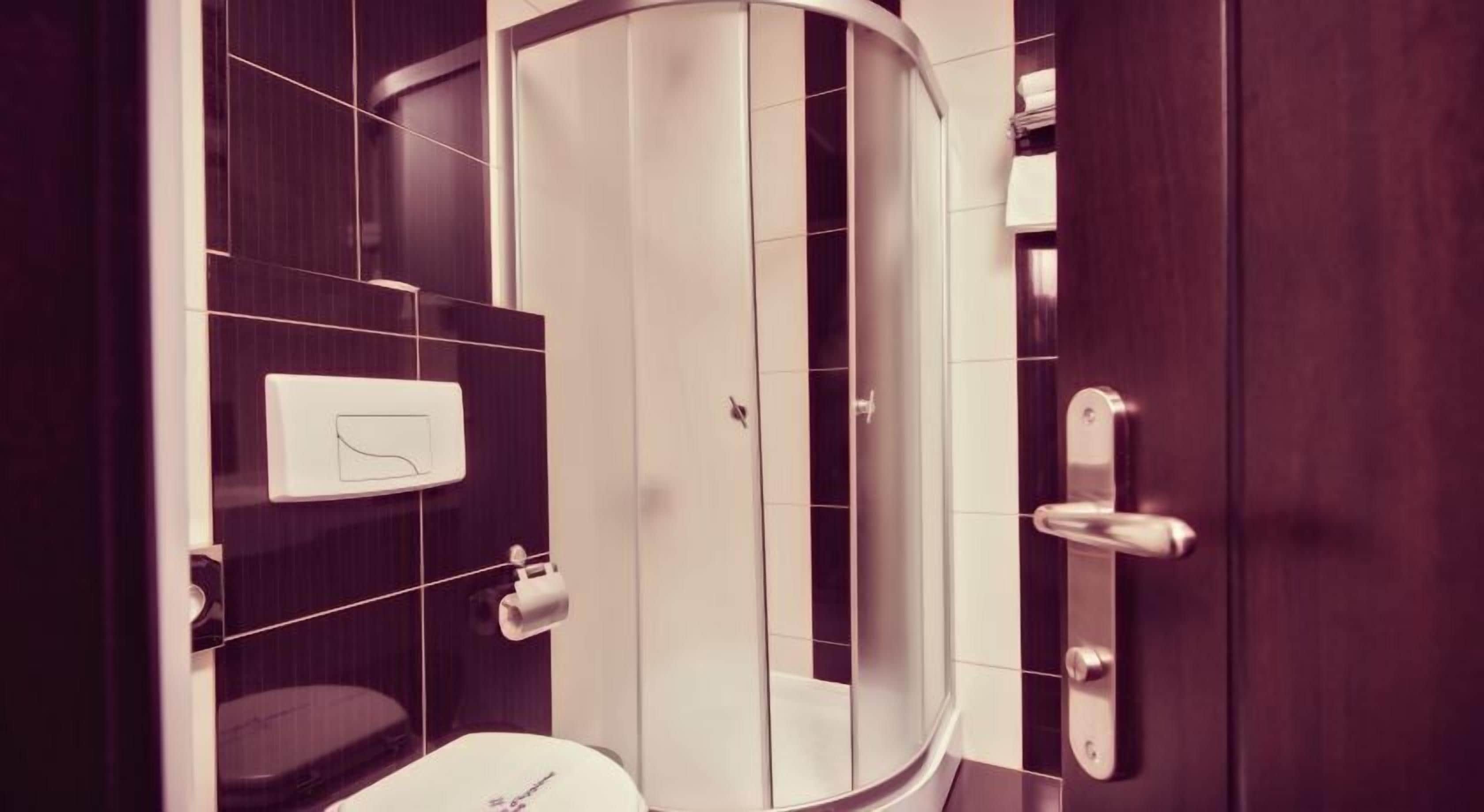 Une salle de bain moderne avec une douche à parois incurvées, des toilettes et un porte-serviettes.