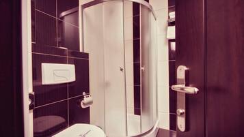 Une salle de bain moderne avec une douche à parois incurvées, des toilettes et un porte-serviettes.