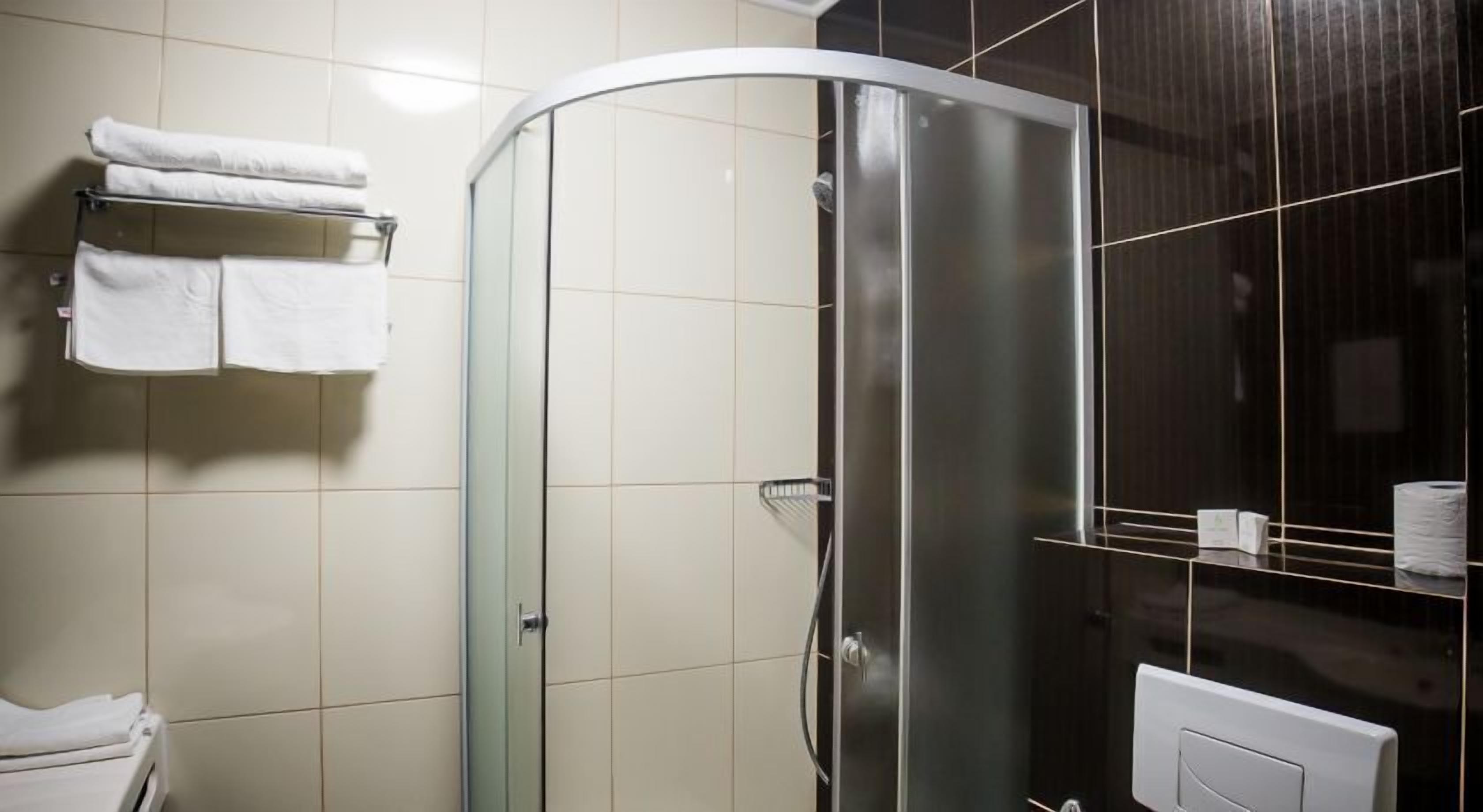 Un baño con cabina de ducha de vidrio, un perchero con toallas dobladas y un inodoro.