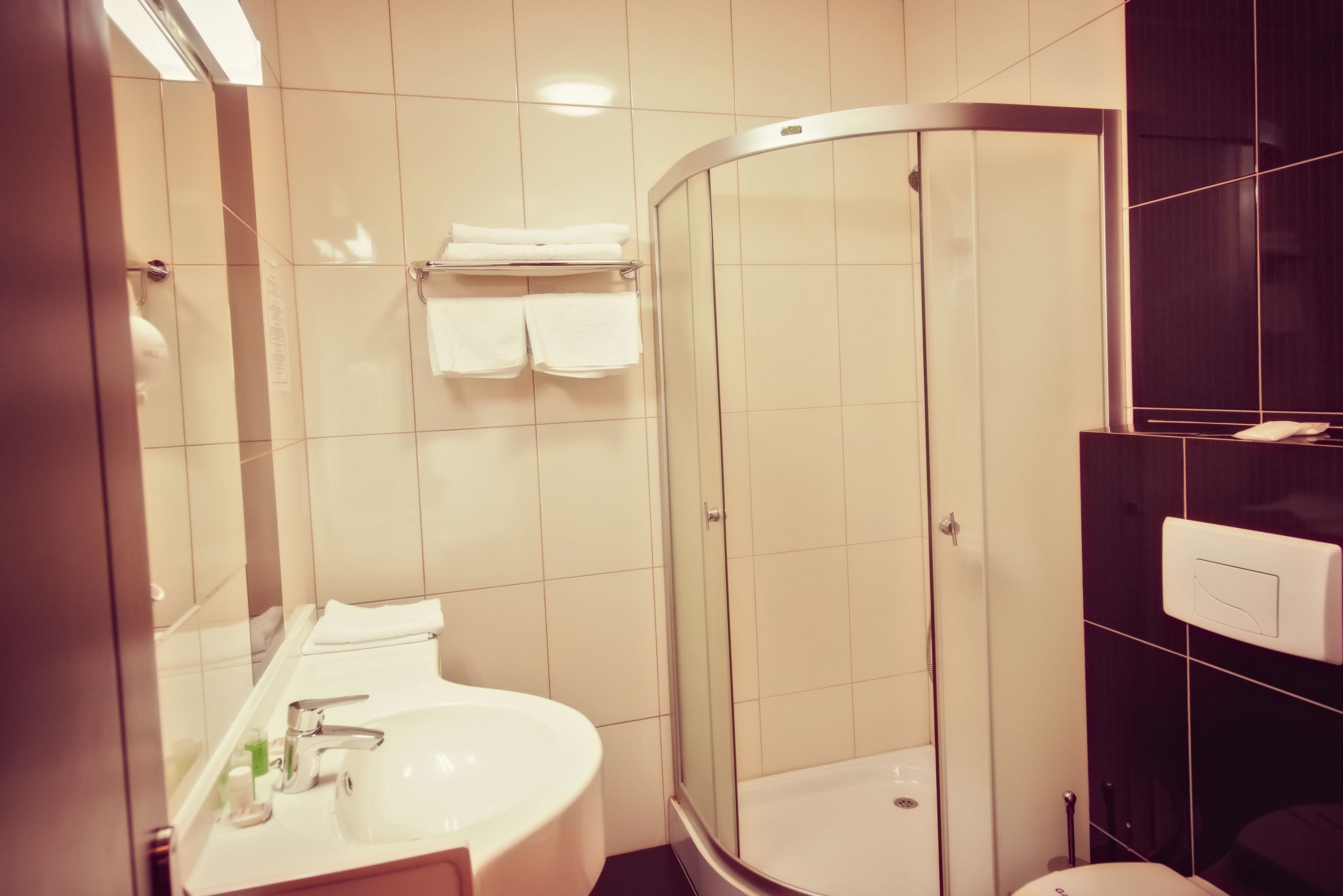 Une salle de bain moderne avec une douche à parois incurvées, un lavabo avec un miroir et un porte-serviettes.