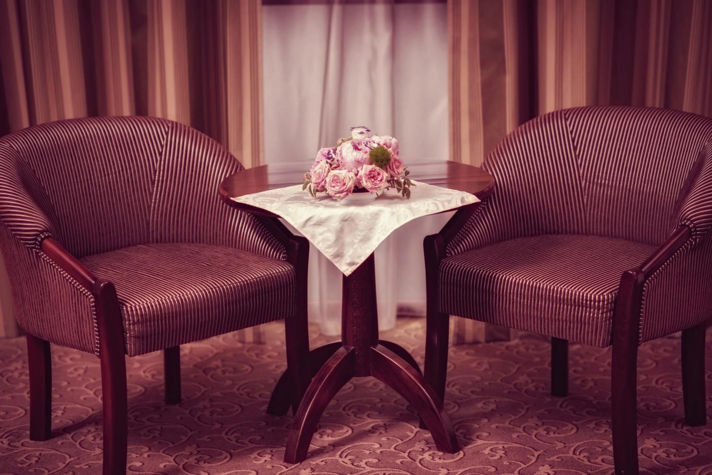 Dos sillones a rayas con una mesa en medio, un centro de mesa floral y una alfombra estampada.