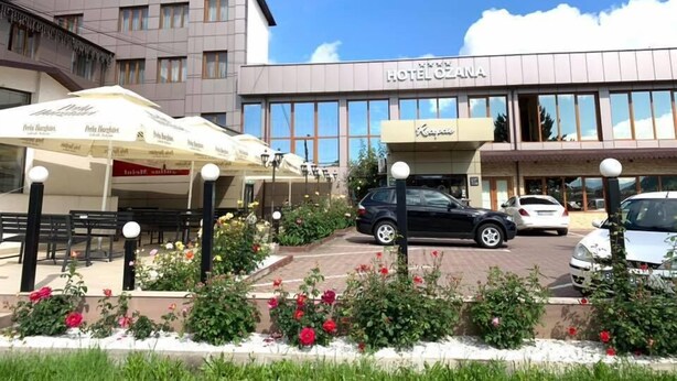 Een hotel met een moderne gevel, terras en een parkeerplaats.