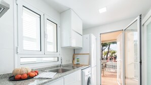A modern kitchen with white cabinets, a granite countertop, a sink, and a washing machine.