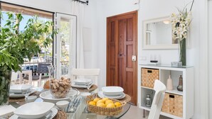 A dining area with a glass table, white plates, and a basket of lemons.