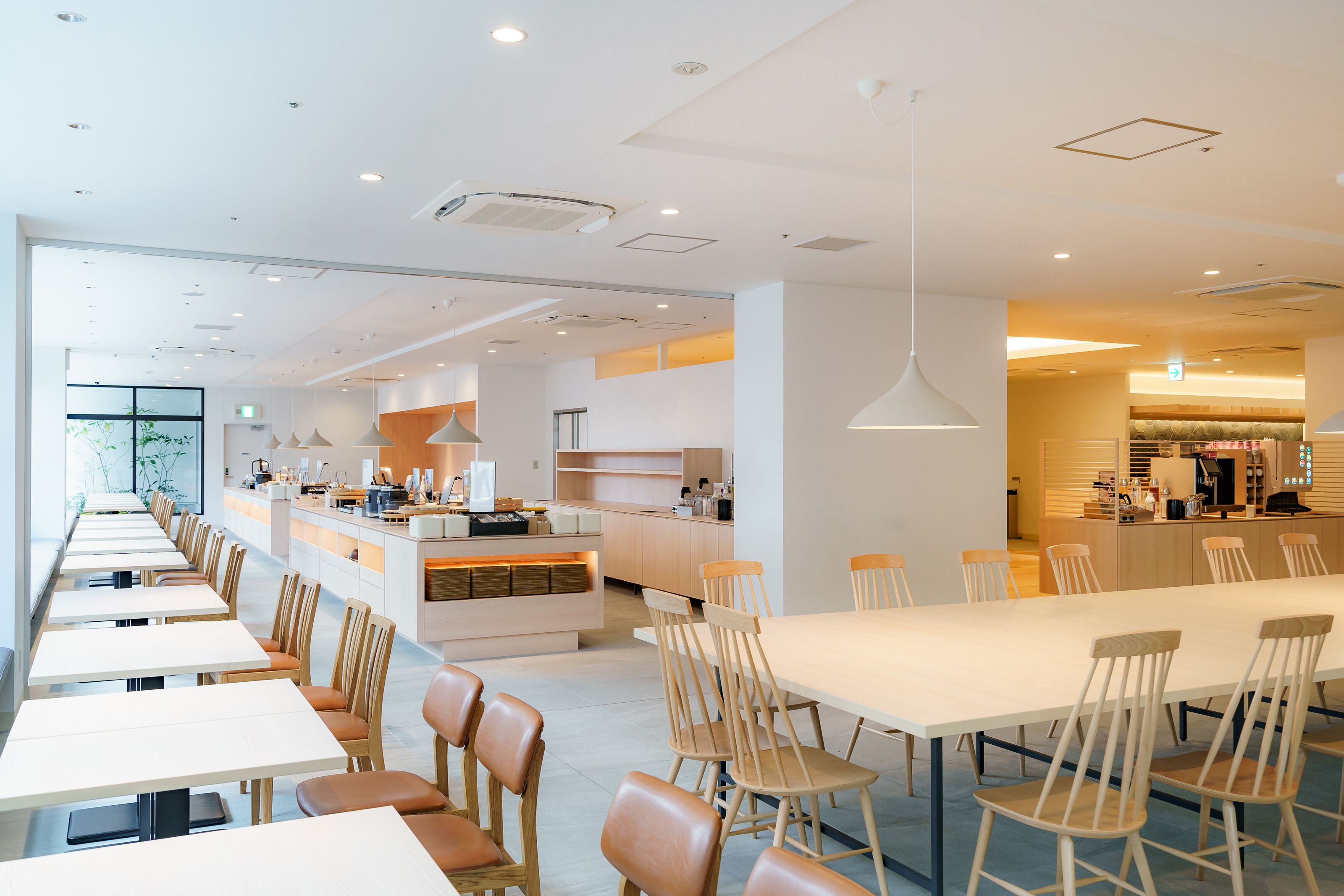 En moderne restaurant med lange fællesspisesteder og båse, et centralt barområde og et lyst, åbent køkken.