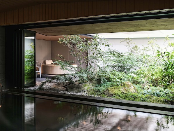 A modern interior with a view of a lush garden, a wooden ceiling, and a seating area with a chair and a table. - REF Kumamoto by VESSEL HOTELS (Kumamoto)