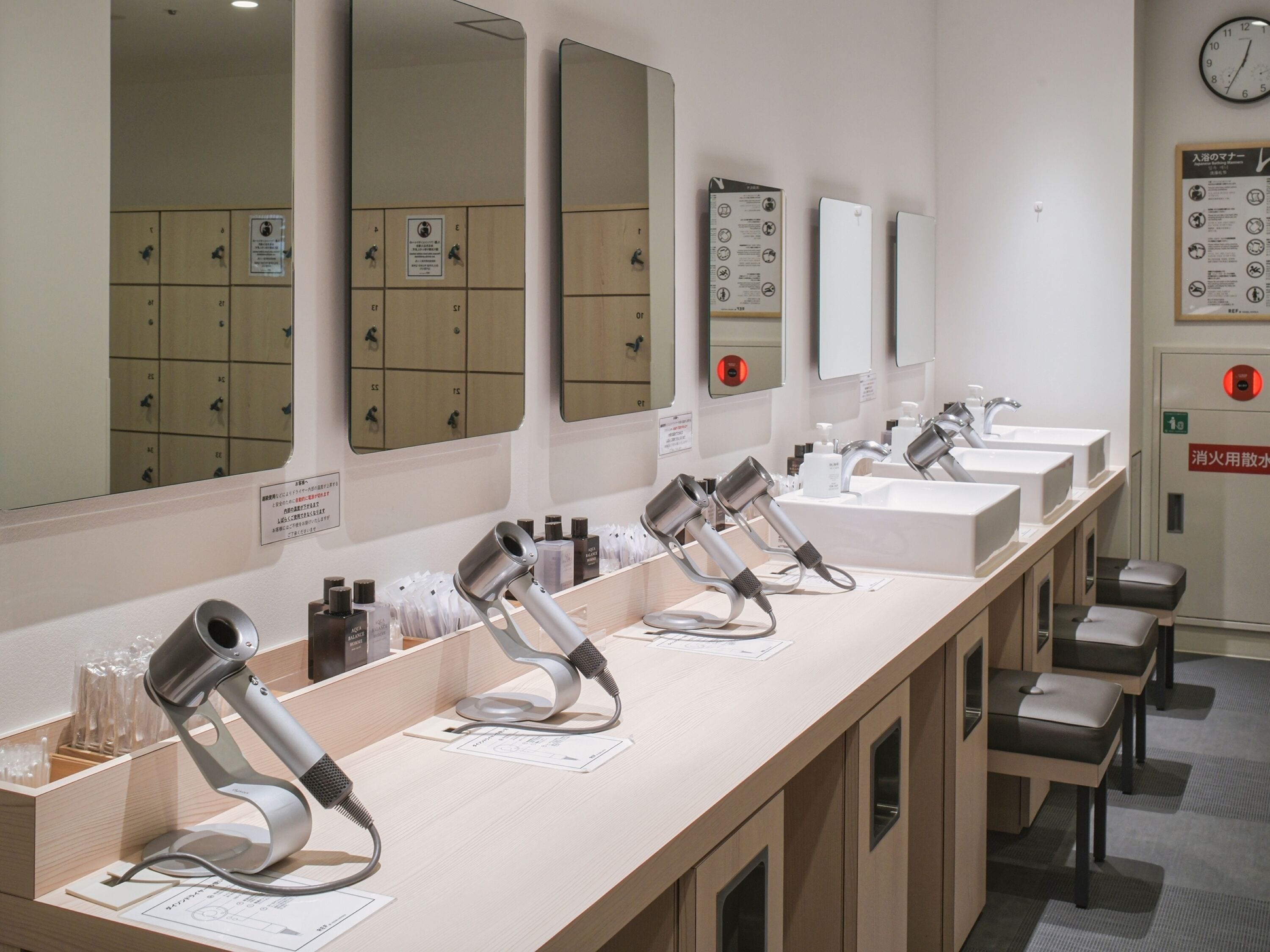 Eine Reihe von Haartrocknern und Waschbecken in einer öffentlichen Toilette.
