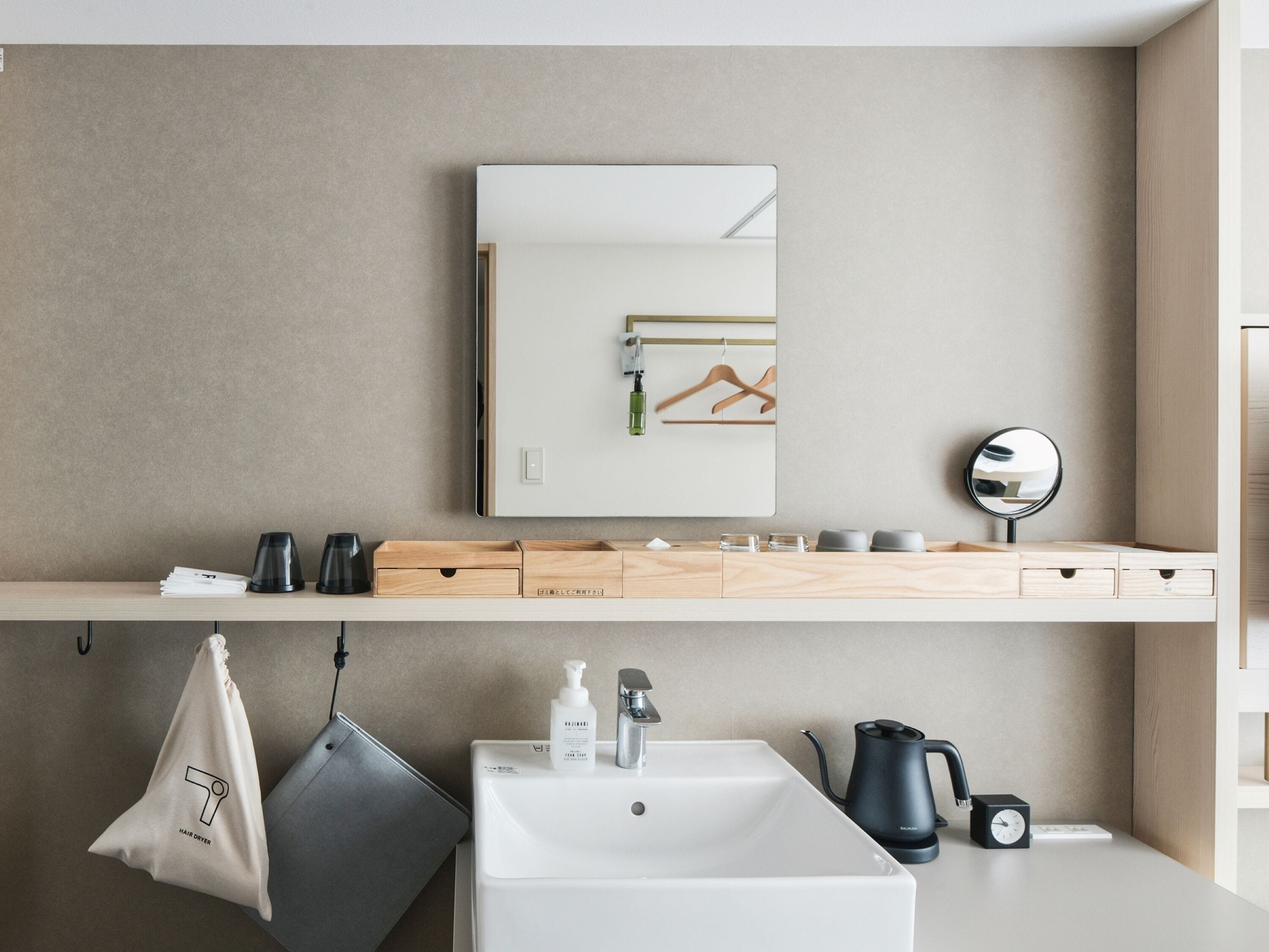 A modern bathroom with a large mirror, a sink, and a towel hanging on a hook.