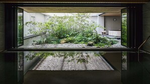 A modern interior space with a glass enclosure displaying an outdoor garden area.