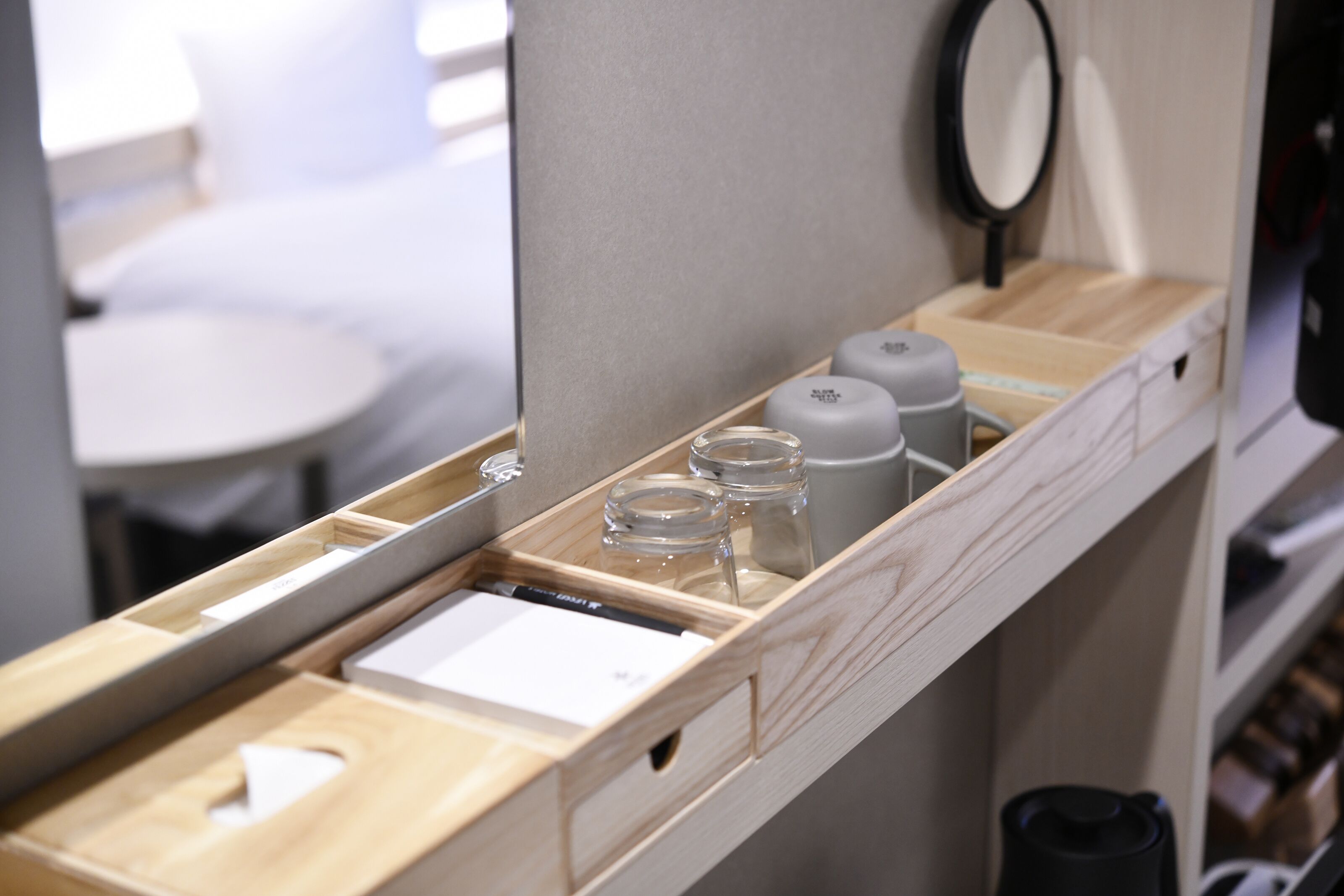 Una encimera de madera con un espejo, una mesita y un cajón con una hoja de papel blanca.
