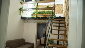 Ein kompakter Wohnraum mit Schlafkoje, Treppe, Sofa und kleinem Tisch.