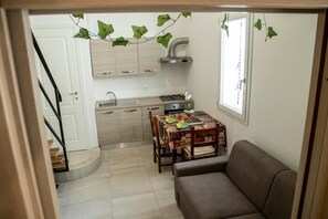 A compact kitchen with a dining table and a sofa.