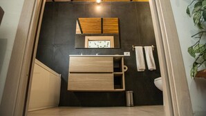 Ein kleines Badezimmer mit einem Holzwaschtisch, einem Spiegel und einer Toilette.