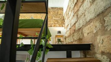 Un interno moderno con una parete in pietra, una panca di legno e una pianta sospesa.
