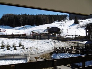 Ein Skigebiet mit Sessellift, überdachtem Bereich und verschneiter Landschaft.