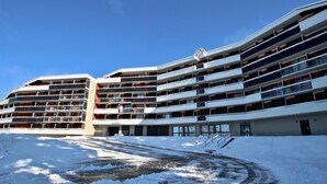 A multi-story hotel with a curved facade, balconies on each floor, and a snow-covered ground. - Southwest cabin studio 4/6 pers near slopes in Chamrousse (Chamrousse)