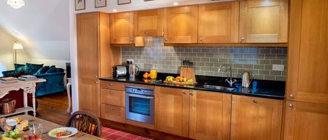 A modern kitchen with wooden cabinets, a built-in oven, and a black countertop.