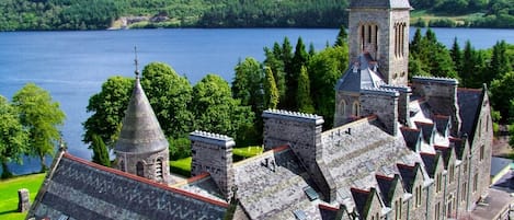 A historic building with multiple towers and a large body of water in the background.