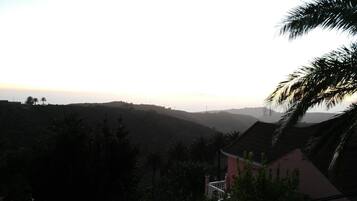 Vista de un paisaje montañoso con una casa en primer plano.