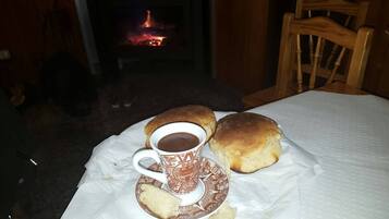 Une table avec une tasse de café, deux petits pains et une assiette posée sur une nappe.