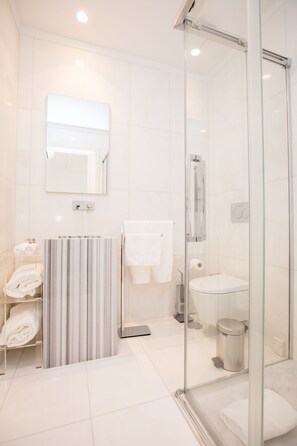 Une salle de bain moderne avec une douche à l’italienne en verre, un meuble-lavabo en marbre et une porte en verre.