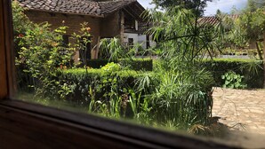 A courtyard with a stone pathway, a brick building, and lush greenery. - Rancho Coyotepec  (Zacatlán)
