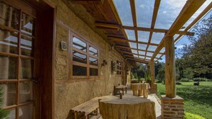 A rustic wooden building with a covered patio area, featuring wooden benches and a central round table. - Rancho Coyotepec  (Zacatlán)
