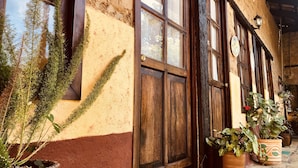 A building with wooden doors and windows, potted plants, and a tiled floor. - Rancho Coyotepec  (Zacatlán)