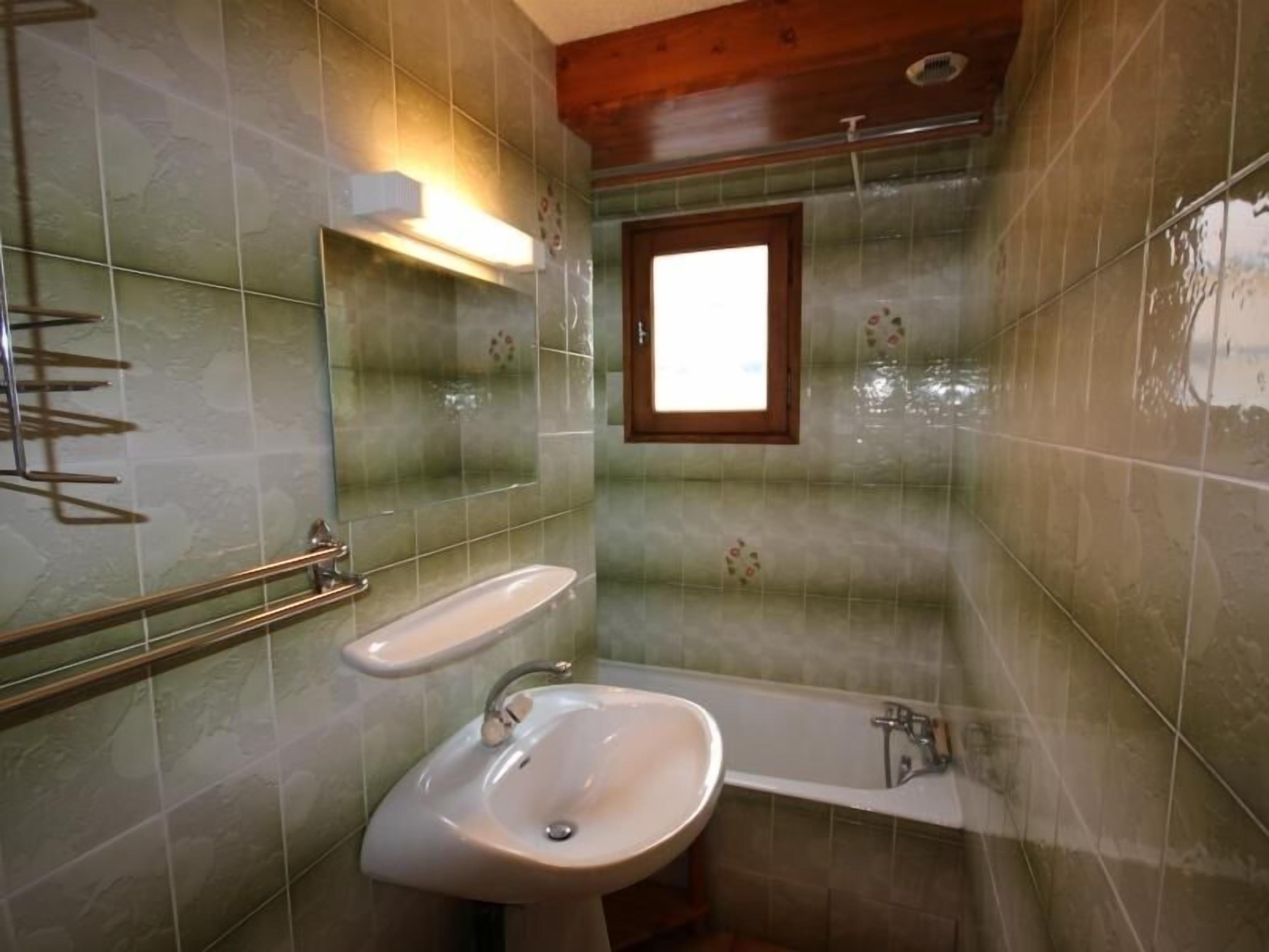 A bathroom with a sink, bathtub, and a window.