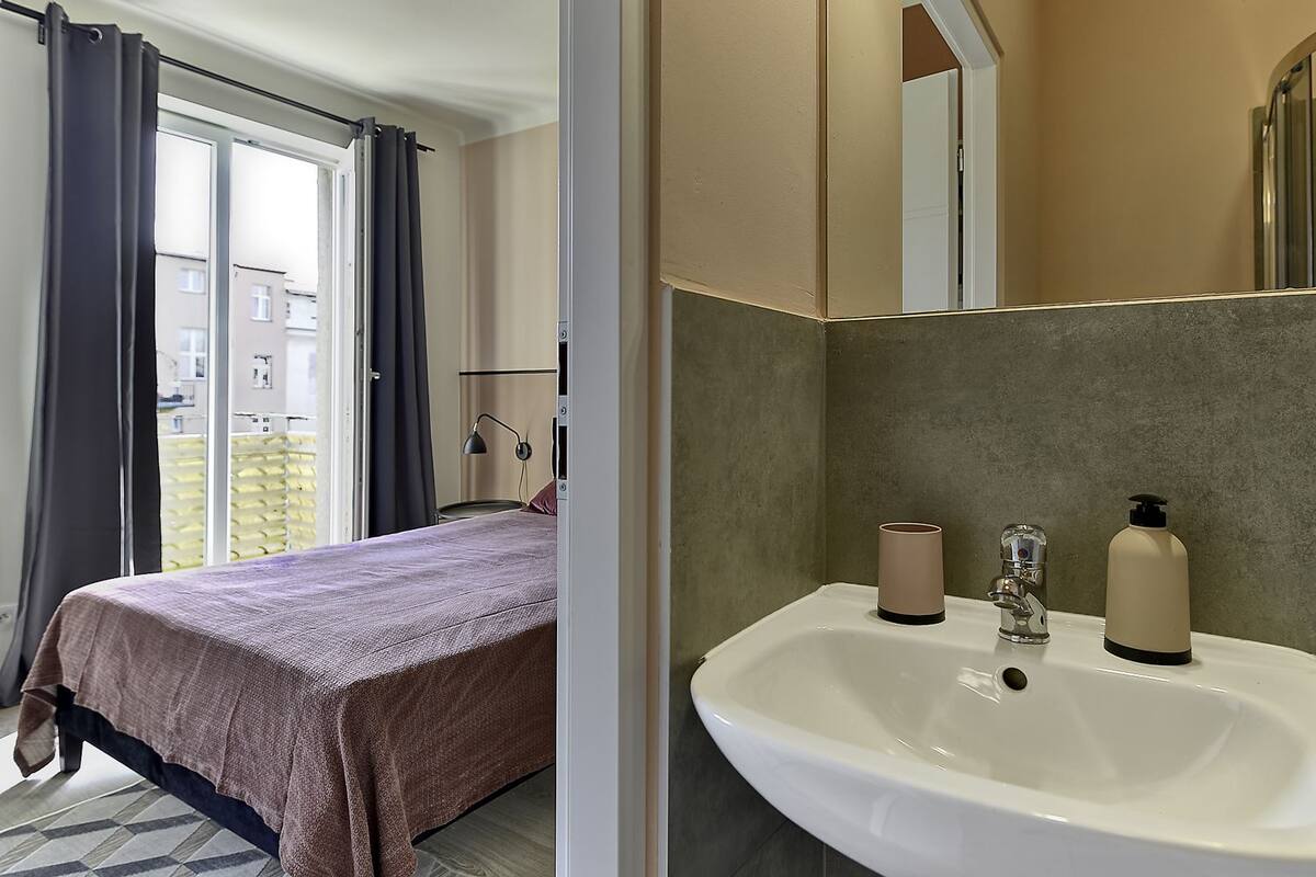 A bedroom with a bed, a bedside lamp, and a window with curtains.