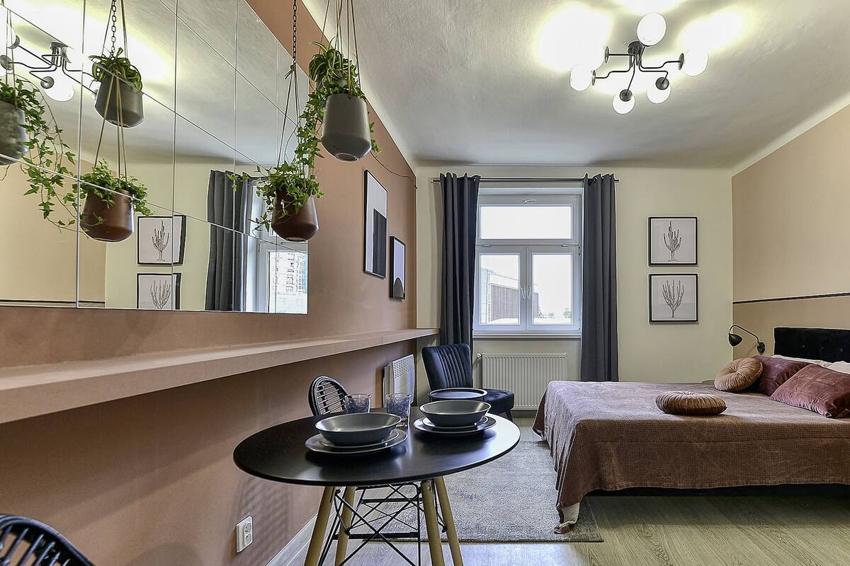 A modern bedroom with a bed, bedside table, and a dining area with a table and chairs.
