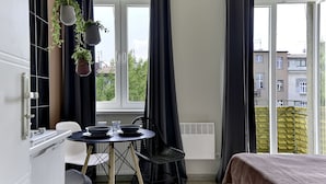 Una camera moderna con un tavolo da pranzo, sedie e un letto. Ci sono piante in vaso appese al soffitto e una finestra con tende.