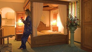 A four-poster bed with a canopy, a wooden nightstand with a lamp, a wooden wardrobe, and a potted plant. - Gasthof Mühle Natur- & Wanderhotel (Rinchnach)