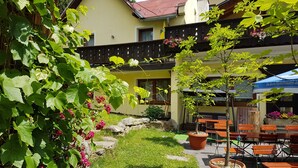 A courtyard with a yellow building, outdoor seating, and a small tree. - Gasthof Mühle Natur- & Wanderhotel (Rinchnach)