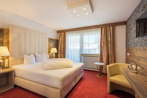 A hotel room with a large bed, a desk, a chair, a lamp, and a view of the outdoors. - Hotel ad LACA (See)