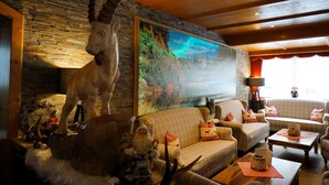 Una sala de estar acogedora con una pared de piedra, un cuadro grande, un conjunto de sofá y una estatua decorativa de ciervo.