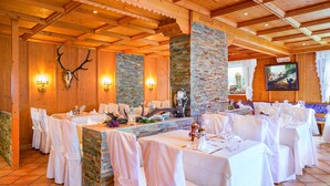 Un restaurante con vigas de madera y pilares de piedra, manteles blancos y una decoración con cráneo de ciervo.