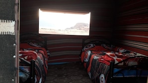A room with two beds, a window with a view of a desert landscape, and a patterned wall. - Bedouin Sunrise camp (Wadi Rum)